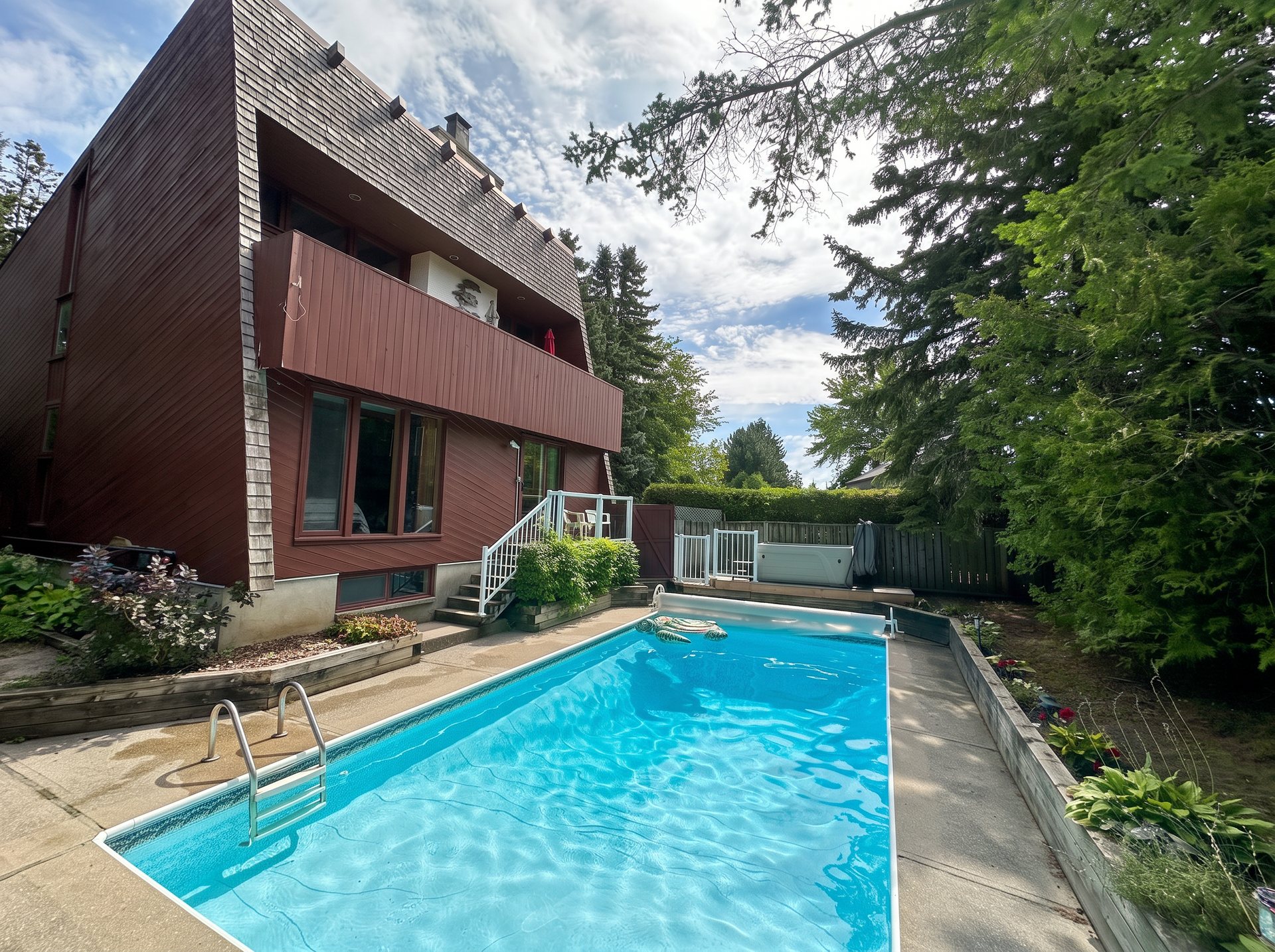 Chalet exterior with private pool and hot tub on a summer day